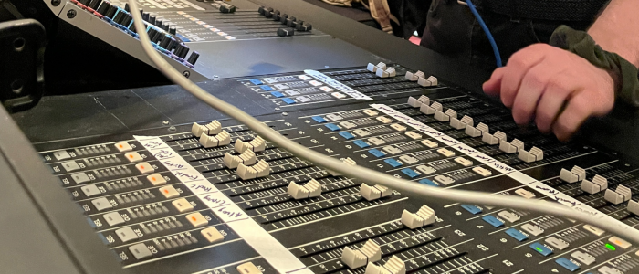 A sound board in use with rows of faders at various levels.