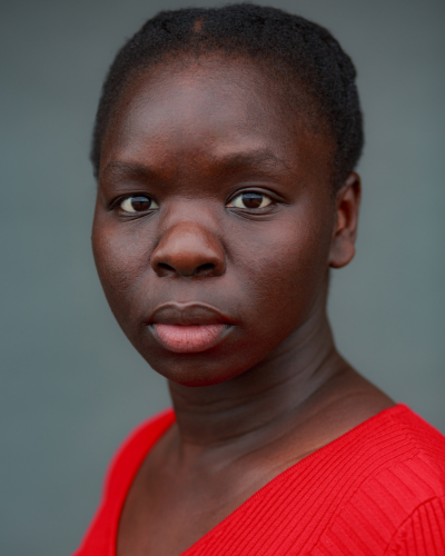 Portrait of Akur Oryem, a black woman with sort dark hair wearing a bright red top.