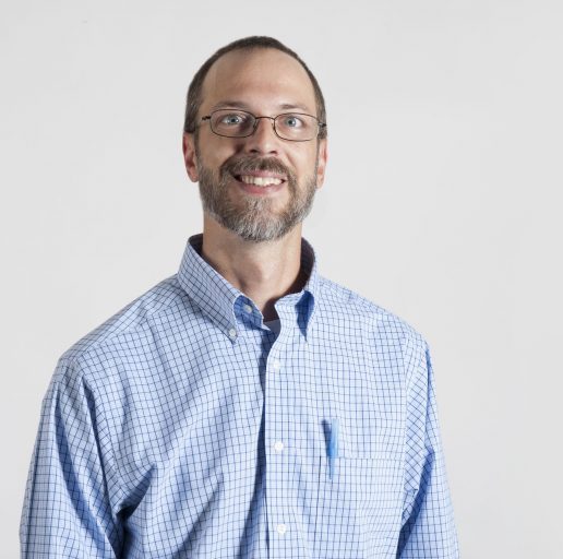 Portrait of a smiling man wearing glasses and a blue button-down shirt