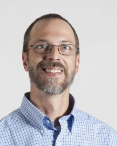 Portrait of a smiling man wearing glasses and a blue button-down shirt