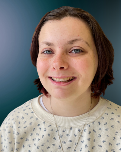 Portrait of Caelyn Dorsey, a young white woman with dark hair and a big smile