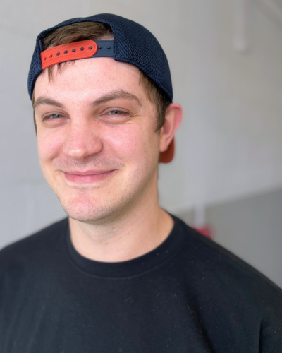 Portrait of Cody Tellis Rutledge, a white college student wearing a backward baseball cap and dark t-shirt