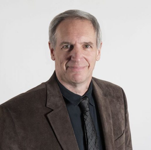 Portrait of a white man in brown blazer