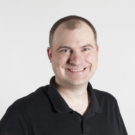 Portrait of a white man in a dark polo shirt.