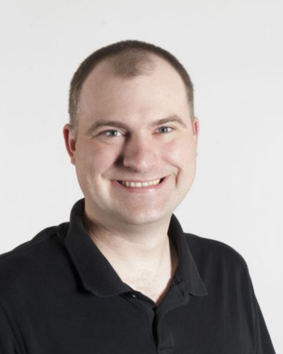Portrait of a white man in a dark polo shirt.