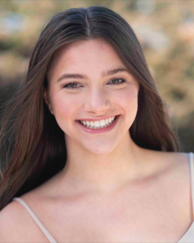 Portrait of Eliza Anderson, a white college student with long straight brown hair and a big smile.