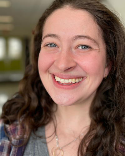 Portait of Hannah Trobaugh, a white graduate student with long, wavy, dark hair and a big smile.