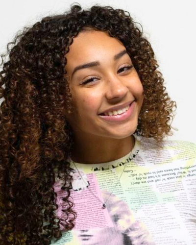 Portrait of Liliana Macintosh, a BIPOC college student with long tight curls and a big smile