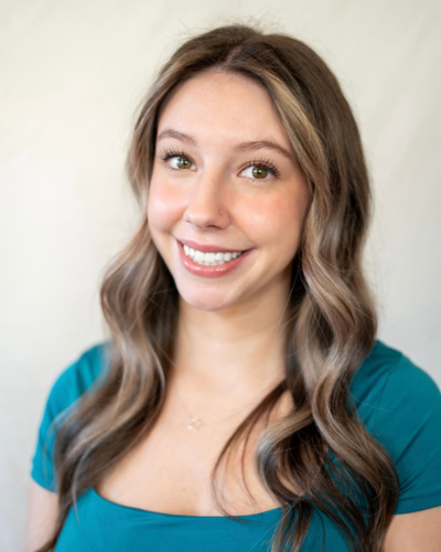 Portrait of Lily Rae O'Niel, a white college student with long brown hair with sof curls, wearing a teal top