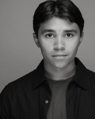 Portrait of Mark Sadowski, a college student with dark hair and an angular ace, wearing an open button down and dark t-shirt
