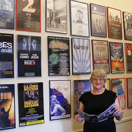 Portait of a woman standing in front of a wall of show posters