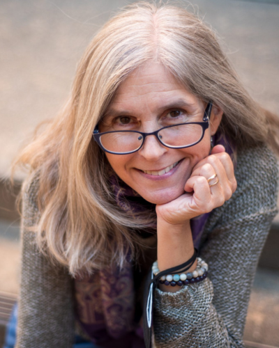 Portrait of Michelle Polgar, a white woman with glasses and a friendly smile, looking at the camera.