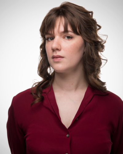 Portrait of Morgan Hyrmack, a young white woman with dark wavy hair, wearing a burgundy blouse.