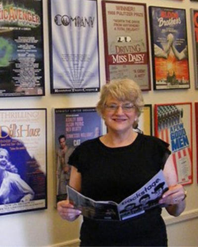 Portrait of a woman standing in front of a wall of show posters