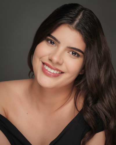 Portrait of Sandy Borrero, a smiling hispanic graduate student with long straight dark hair.