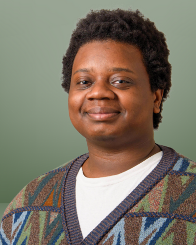 Portrait of Tyler Ely, a black college student with a sweet smile, wearing a geometrically patterned sweater
