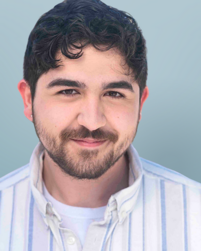 Portrait of Will Naraghi, a college student with facial hair and dark hair, wearning a white button-down shirt with light blue stripes