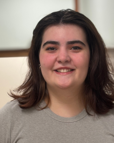 Portrait of Anna Tenner, a young white woman with medium length brown hair, smiling at the camera