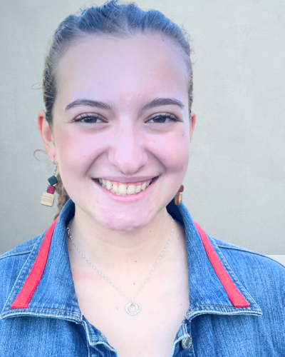 Portrait of a college student with her light brown hair pulled back, smiling and wearing a jean jacket.