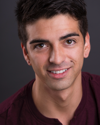 Portrait of a college student with thick dark hair and bushy eyebrows, wearing a burgundy polo shirt.