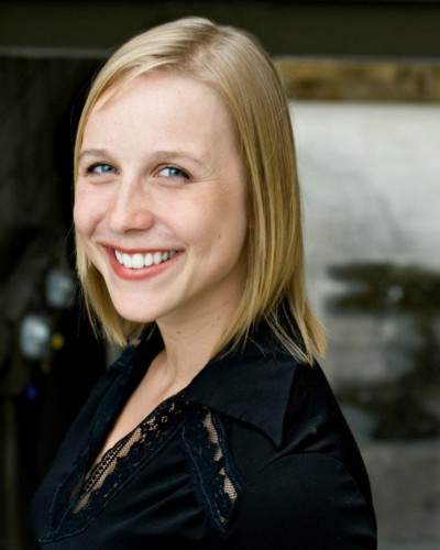 Portrait of Lilian Ransjin, a white professor with straight blond hair, wearing a black top, smiling at the camera