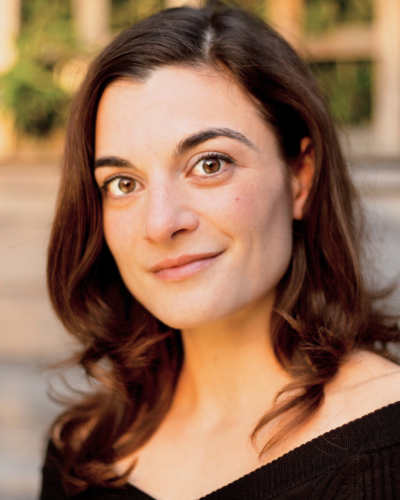 Portrait of a woman with long dark hair and big brown eyes, wearing a black top.