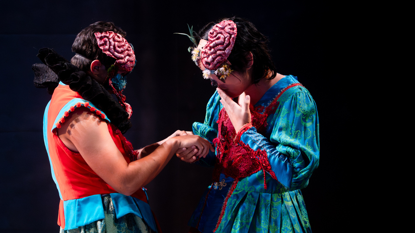 Zombie Rosencrantz and Guildenstern, dressed in brightly colored garb, examine something in their hands.