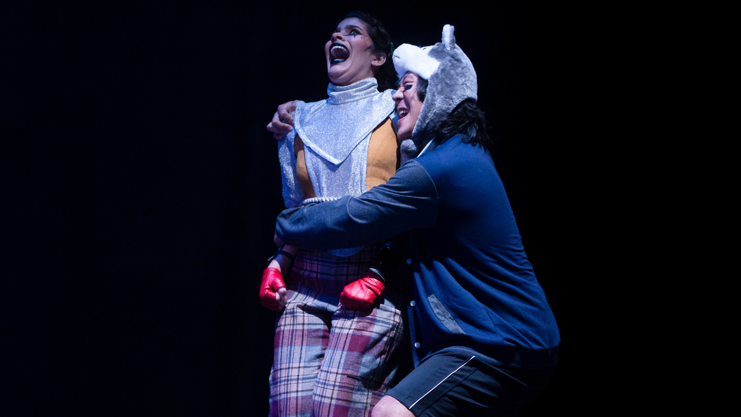 Caliban, wearing a Husky hat, frightens a tied up Lady M.
