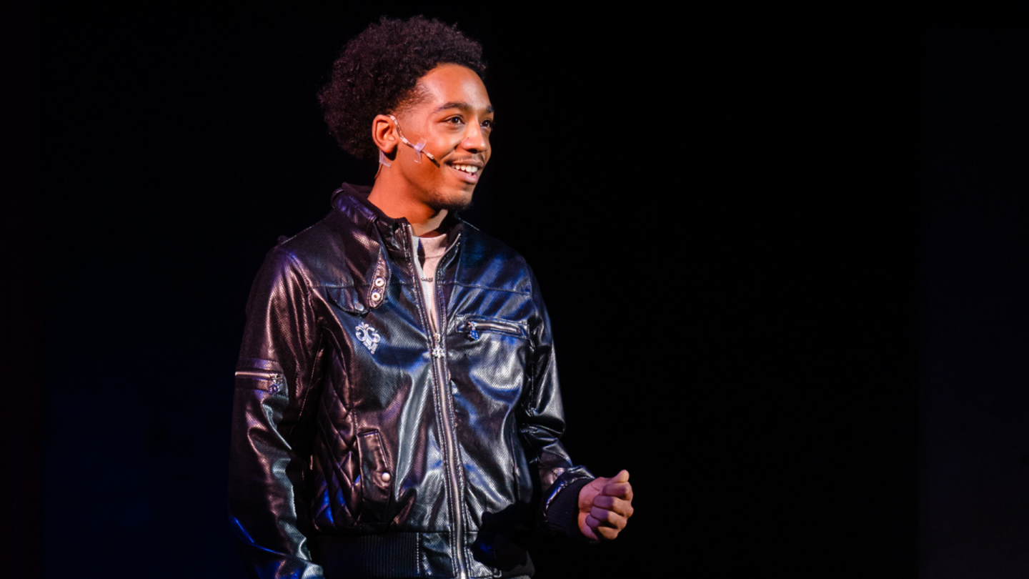 Oliver, wearing a black leather jacket, smiles as he meets Celia.